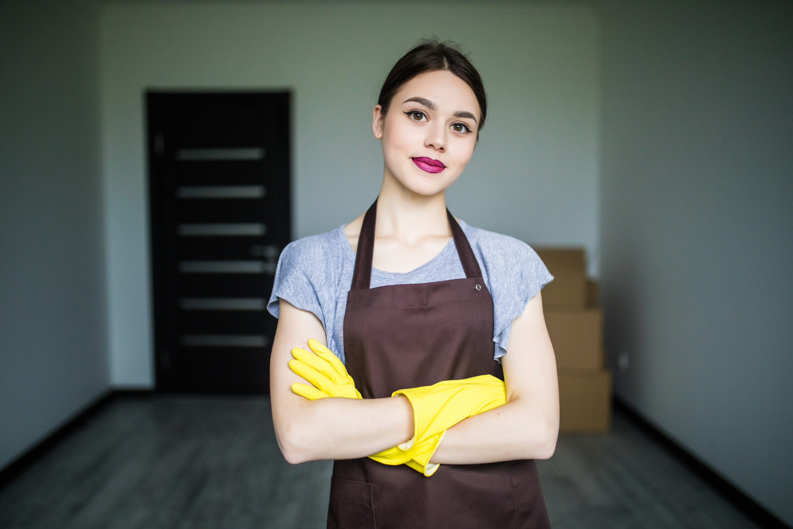 Young cleaning lady putting on rubber gloves, getting ready for spring cleaning